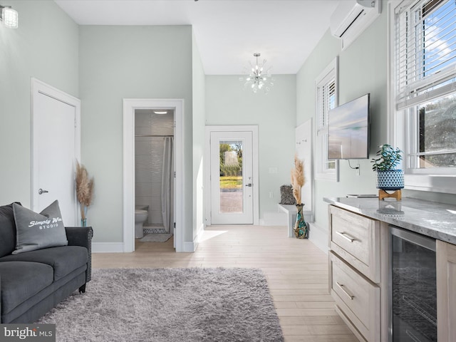 living room with a wall unit AC, wine cooler, plenty of natural light, and light wood-type flooring