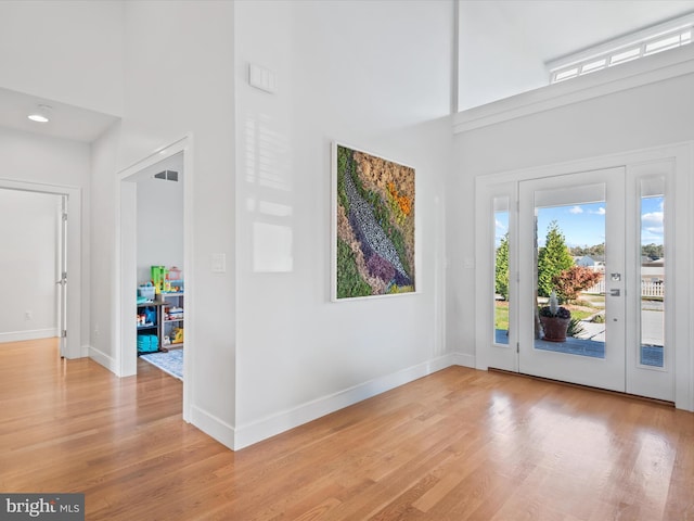 foyer featuring a towering ceiling and light hardwood / wood-style flooring