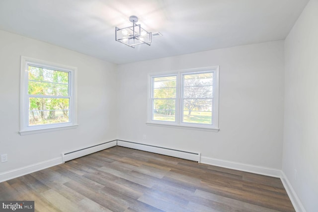 unfurnished room with a wealth of natural light, wood-type flooring, and a notable chandelier