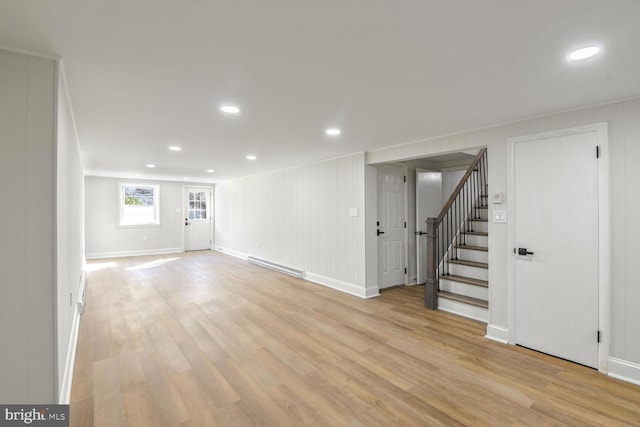 interior space featuring a baseboard radiator, light hardwood / wood-style flooring, and wood walls