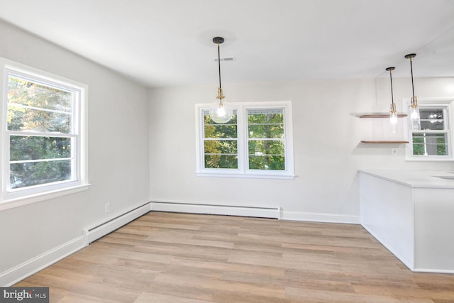 unfurnished dining area featuring light wood-type flooring, a wealth of natural light, and a baseboard heating unit