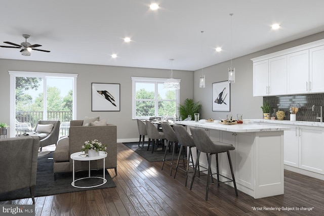 kitchen featuring white cabinets, a center island, backsplash, hanging light fixtures, and a breakfast bar