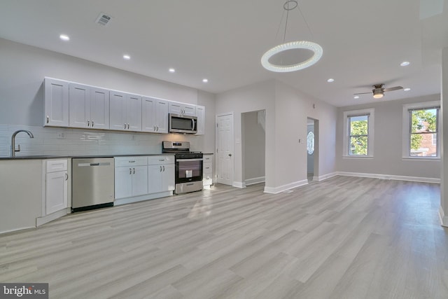 kitchen featuring sink, white cabinets, hanging light fixtures, light wood-type flooring, and stainless steel appliances