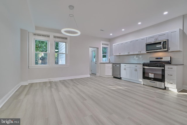 kitchen featuring stainless steel appliances, backsplash, decorative light fixtures, white cabinets, and light wood-type flooring