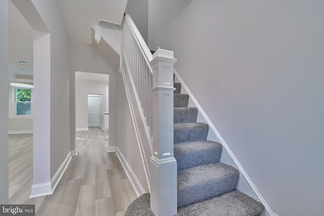 stairs featuring high vaulted ceiling and wood-type flooring