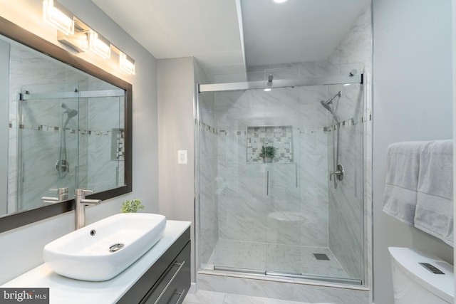 bathroom with walk in shower, vanity, and toilet