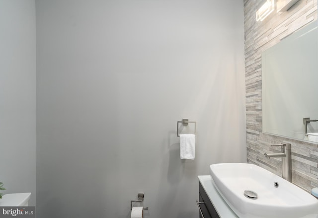 bathroom featuring vanity, toilet, and decorative backsplash