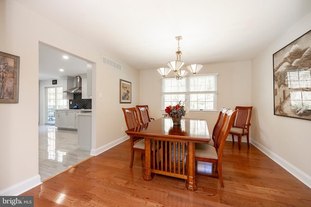 dining area featuring a healthy amount of sunlight, a notable chandelier, and light hardwood / wood-style floors