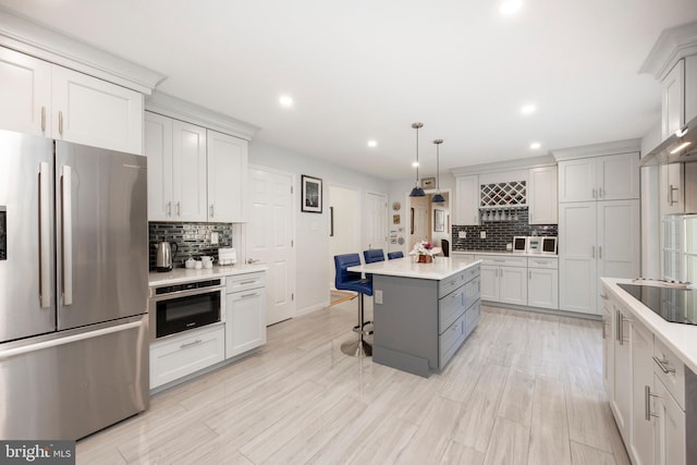 kitchen featuring tasteful backsplash, stainless steel appliances, a center island, hanging light fixtures, and a breakfast bar area