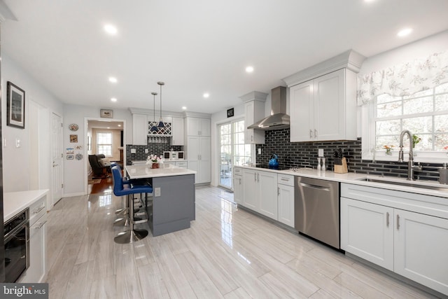 kitchen featuring dishwasher, plenty of natural light, hanging light fixtures, and wall chimney exhaust hood