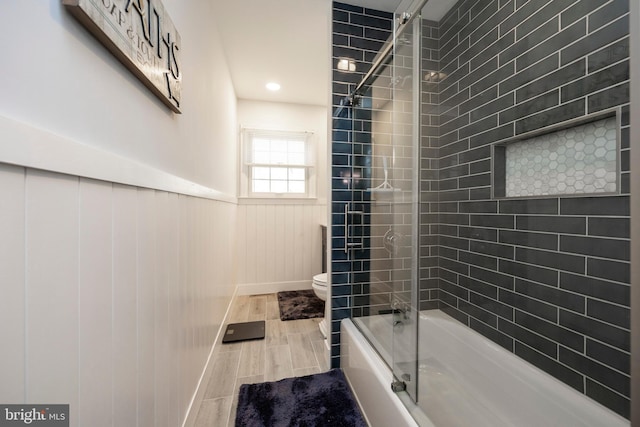 bathroom with hardwood / wood-style flooring, toilet, and enclosed tub / shower combo