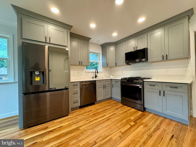 kitchen with appliances with stainless steel finishes, light hardwood / wood-style flooring, plenty of natural light, and sink