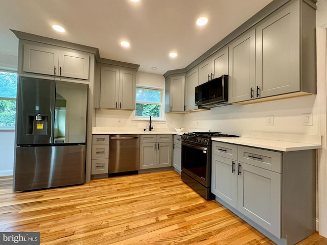 kitchen featuring gray cabinetry, sink, stainless steel appliances, and light hardwood / wood-style floors