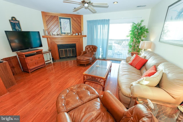 living area with a glass covered fireplace, recessed lighting, visible vents, ceiling fan, and wood finished floors