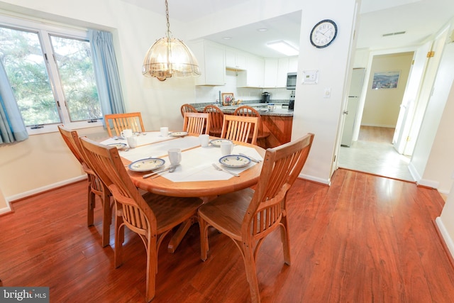 dining space featuring a chandelier, wood finished floors, and baseboards