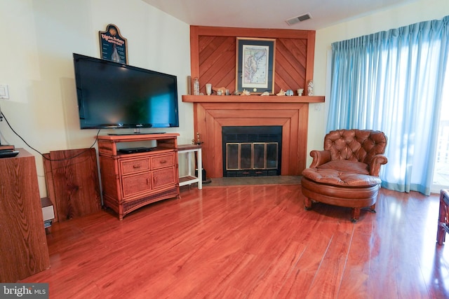 sitting room with visible vents, a glass covered fireplace, and wood finished floors