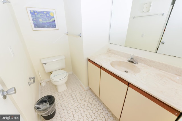 half bathroom featuring vanity, baseboards, and toilet