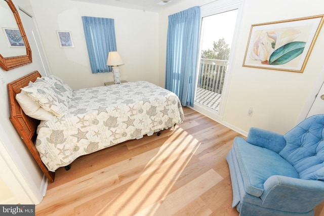 bedroom with access to exterior, light wood finished floors, and baseboards