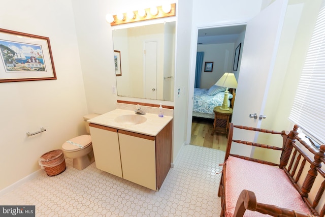 bathroom featuring toilet, vanity, and baseboards