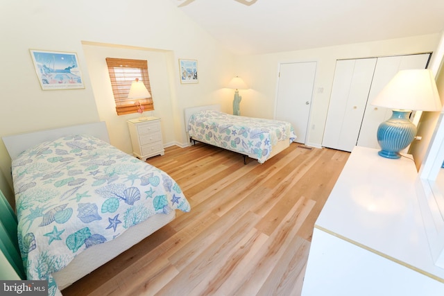 bedroom with light wood-style floors, a closet, and vaulted ceiling