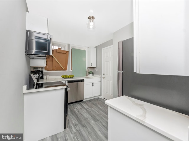 kitchen with white cabinets, light wood-type flooring, stainless steel dishwasher, and sink