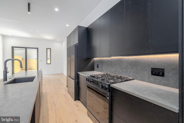 kitchen with backsplash, sink, light hardwood / wood-style flooring, gas stove, and stainless steel refrigerator