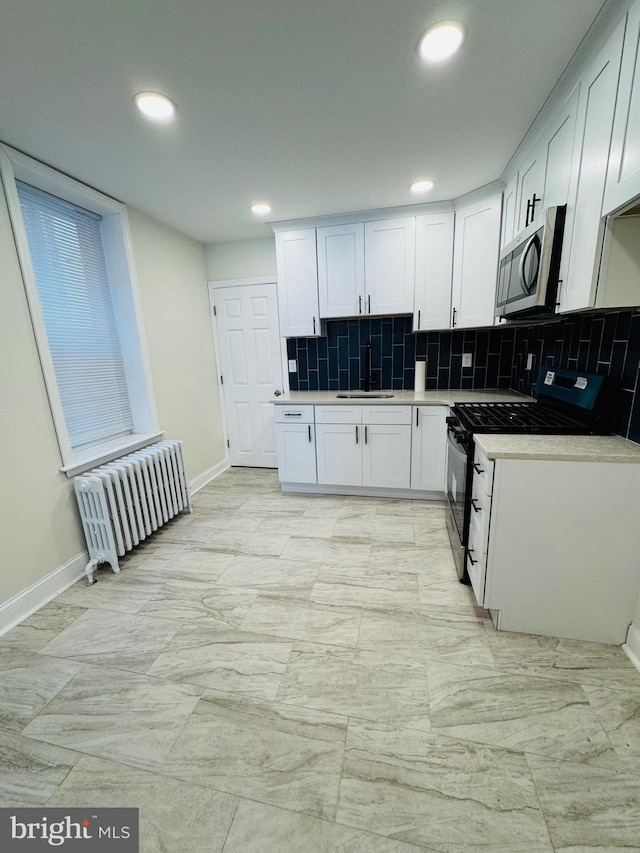 kitchen with range, white cabinets, sink, and radiator heating unit