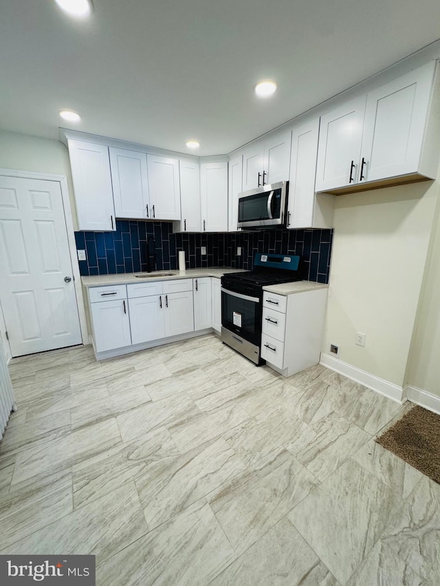 kitchen with white cabinetry, stainless steel appliances, and backsplash