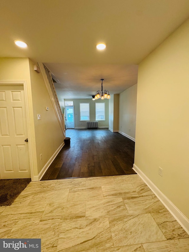 corridor with radiator, a notable chandelier, and hardwood / wood-style flooring