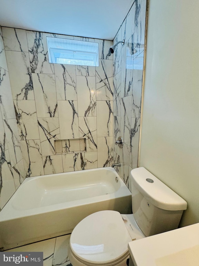 bathroom with toilet and tiled shower / bath