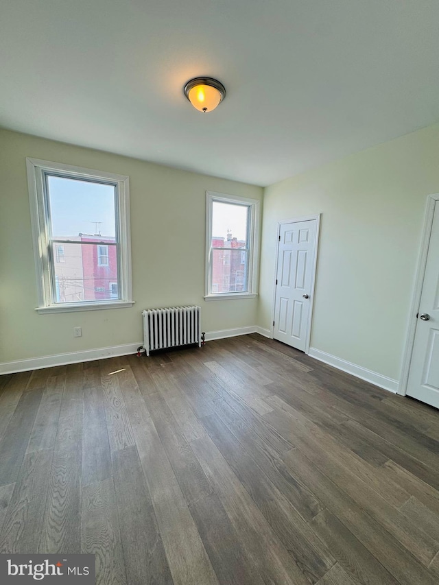 unfurnished room featuring dark wood-type flooring and radiator heating unit