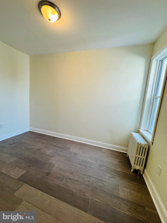 empty room featuring radiator heating unit and dark wood-type flooring