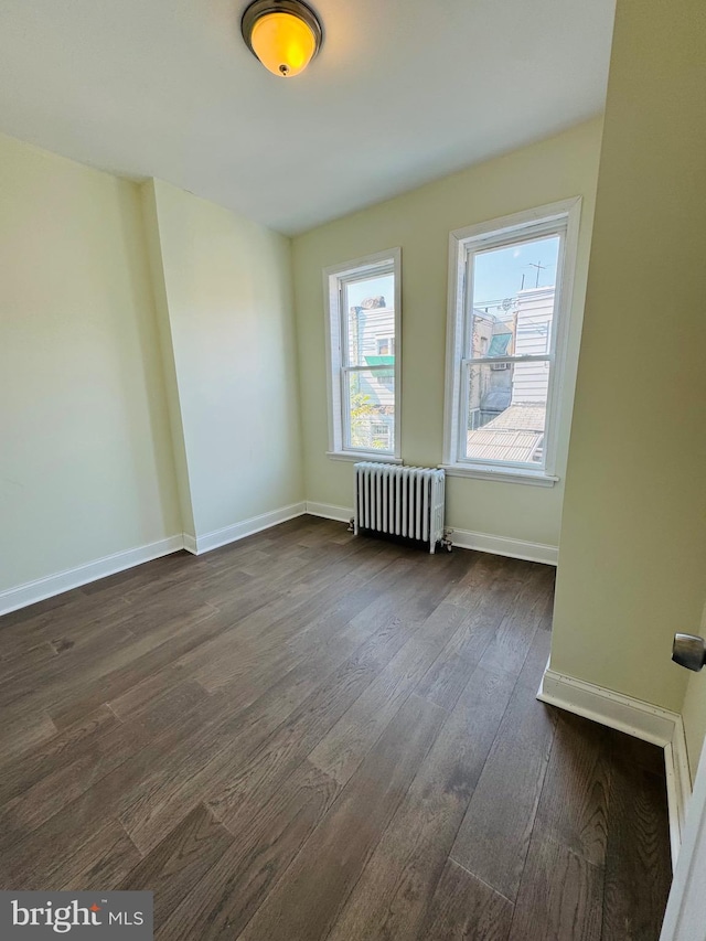 unfurnished room featuring dark wood-type flooring and radiator heating unit