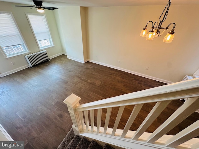 stairway featuring hardwood / wood-style flooring, radiator heating unit, and ceiling fan with notable chandelier