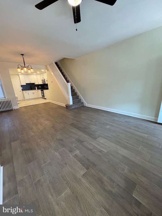 unfurnished living room with dark hardwood / wood-style floors and ceiling fan with notable chandelier