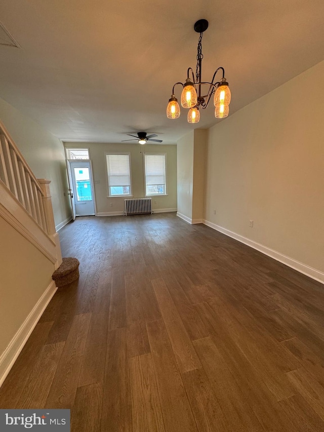 unfurnished living room featuring ceiling fan with notable chandelier, radiator heating unit, and dark hardwood / wood-style floors