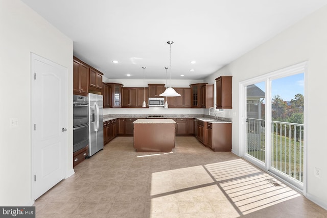 kitchen with stainless steel appliances, sink, a kitchen island, and hanging light fixtures