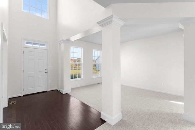 foyer entrance featuring dark wood-type flooring and decorative columns