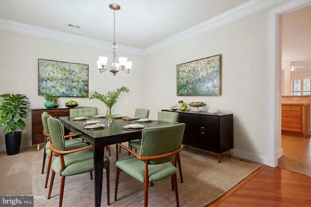 dining area featuring ornamental molding, light wood-type flooring, and an inviting chandelier