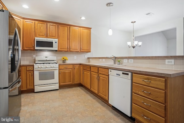 kitchen featuring sink, backsplash, a chandelier, pendant lighting, and white appliances