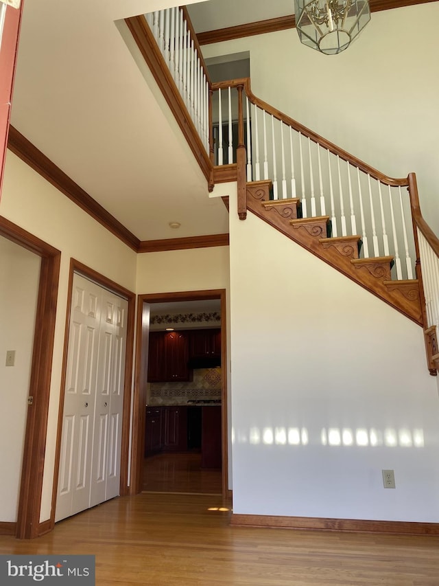 stairs with an inviting chandelier, crown molding, and hardwood / wood-style floors