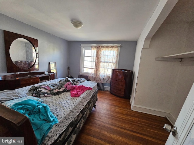 bedroom with radiator heating unit and dark hardwood / wood-style flooring