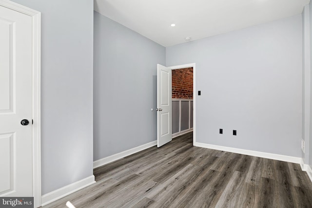 spare room with baseboards and wood finished floors