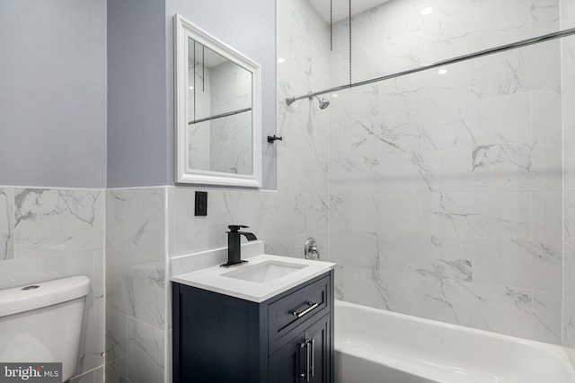 full bathroom featuring vanity, toilet, tile walls, and tiled shower / bath