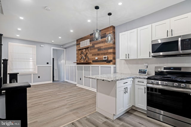 kitchen featuring light stone countertops, light wood-type flooring, white cabinetry, stainless steel appliances, and decorative light fixtures