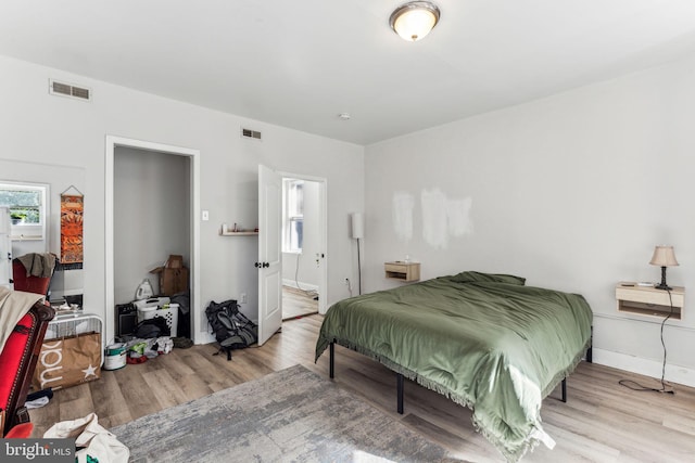 bedroom with ensuite bathroom and light hardwood / wood-style flooring