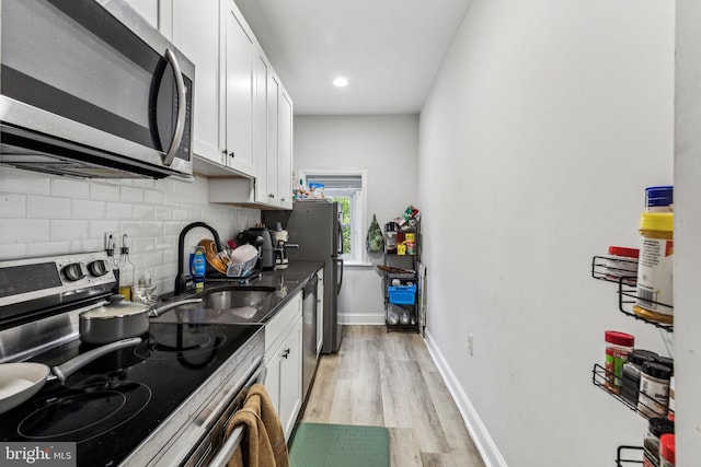 kitchen featuring appliances with stainless steel finishes, sink, light hardwood / wood-style floors, and white cabinets