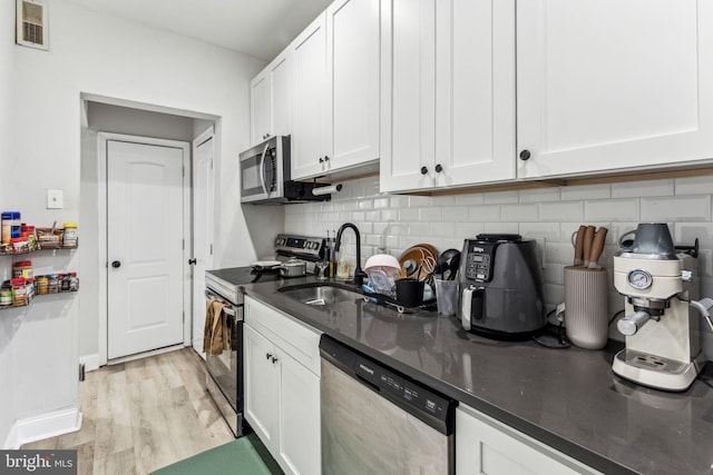 kitchen featuring white cabinetry, light wood-type flooring, appliances with stainless steel finishes, and sink