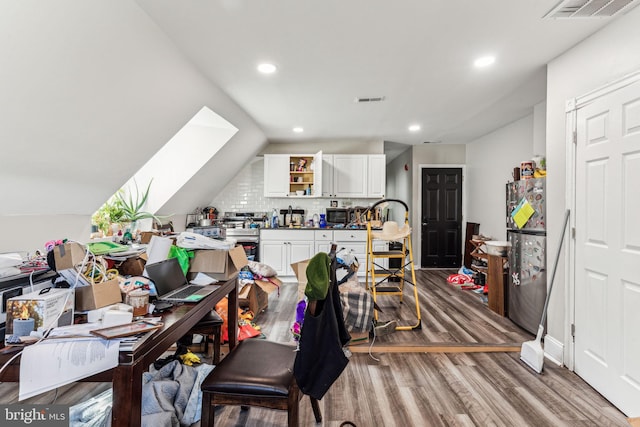 office space with hardwood / wood-style floors and vaulted ceiling with skylight