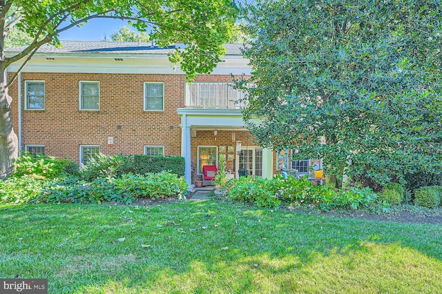 view of front of property featuring a front lawn and a balcony